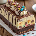 Chocolate Loaf Ice Cream Cake 5 A chocolate loaf ice cream cake topped with chocolate ganache and chocolate shavings, served on a rustic wooden table.