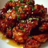 Plate of delicious Honey Chicken garnished with herbs and served with rice.